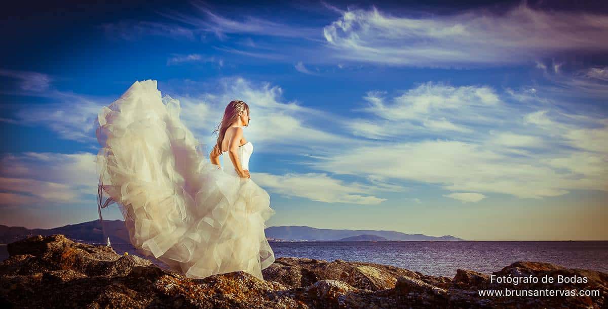 Postboda novia en el acantilado observando el horizonte.